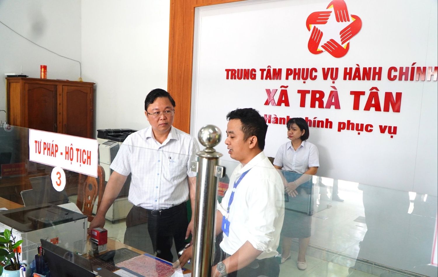 Chủ tịch Ủy ban MTTQ Việt Nam thành phố Lê Trí Thanh (bên trái) trao đổi với cán bộ Trung tâm Phục vụ hành chính công xã Trà Tân. Ảnh: VINH ANH